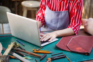 Deri imalatçısı, çevrimiçi pazarlarda satılık ürünler yüklemek için dizüstü bilgisayar kullanıyor..