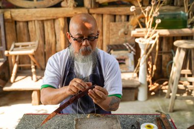 Yakın plan Asyalı deri ustası atölyedeki bir müşteri için deri kemer dikmeye özen gösterir. Deri ustası konsepti..
