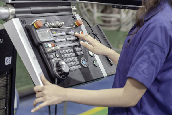 Closeup and crop hand of technician Engineer wearing uniform touch, press the button of automated machinery in industrial workshop.