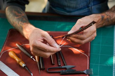 Bir atölyedeki müşteriye yakın plan ve deri el işi dikiş ve deri kahverengi çanta sapı..