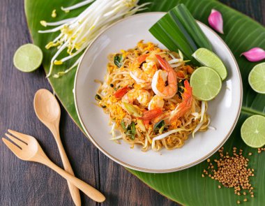 Dünyaca ünlü taze kızartılmış Tayland karidesli erişte tarifi. Beyaz seramik tabak ve kaşıkla süslenmiş sebzeli, millet. Restoran menüsü için yatay fotoğrafçılık