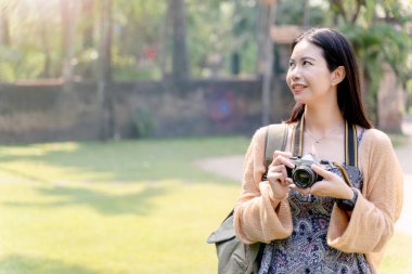 Çok güzel bir Taylandlı turist elinde eski Tayland Lanna tapınağının arka planında sevimli bir gülümseme ile klasik bir kamera tutuyor..