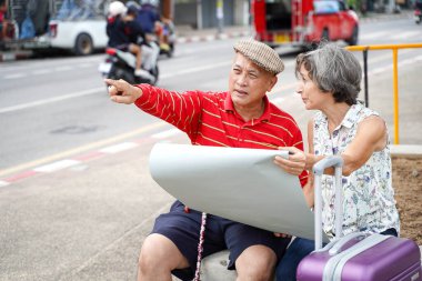 Bir erkek, kentin arka planında yaşlı bayan turistlerin turistik cazibesine giden yolu işaret ediyor. Kıdemli turist konsepti