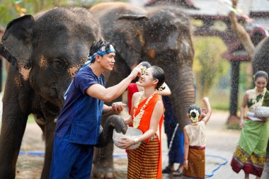 Tayland 'ın kuzeyindeki Tayland' lı genç adam Tayland 'da Songkran su festivali, Chiang Mai, Tayland' da filli güzel bir Taylandlı kadının yanağına pudra sürüyor.