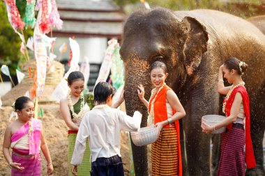 Tayland 'da geleneksel giyinmiş bir grup kadın ve çocuk Tayland Yeni Yıl Festivali' nde su sıçratma oyunu oynuyorlar. Ya da Songkran Festivali 'nde fil ve açık hava kum yığınları eğlenceli bir şekilde yapılıyor..
