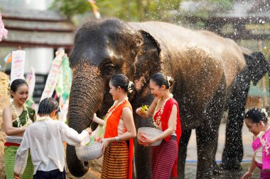 Tayland 'da geleneksel giyinmiş bir grup kadın ve çocuk Tayland Yeni Yıl Festivali' nde su sıçratma oyunu oynuyorlar. Ya da Songkran Festivali 'nde fil ve açık hava kum yığınları eğlenceli bir şekilde yapılıyor..