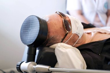 Yaşlı bir hastanın kafasında yakın çekim elektriksel kas uyarısı (EMS). EMS, elektrik akımları kullanılarak kas kasılmalarının ortaya çıkmasıdır. .