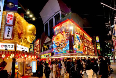 Osaka şehri, Japonya - 09 Aralık 2024: Gece manzarası ve Shinsekai bölgesinde kalabalık olan Japonca ilginç tabela. Shinsekai bölgesi Osaka 'da popüler bir turizm merkezidir.