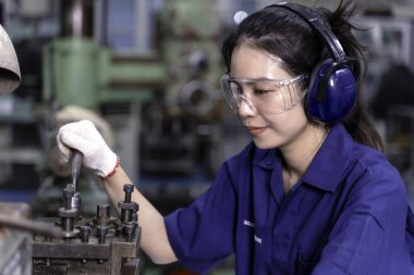 Yakın plan Asyalı endüstriyel mühendis kadın eski model torna ve sondaj makinesi ile çalışıyor..