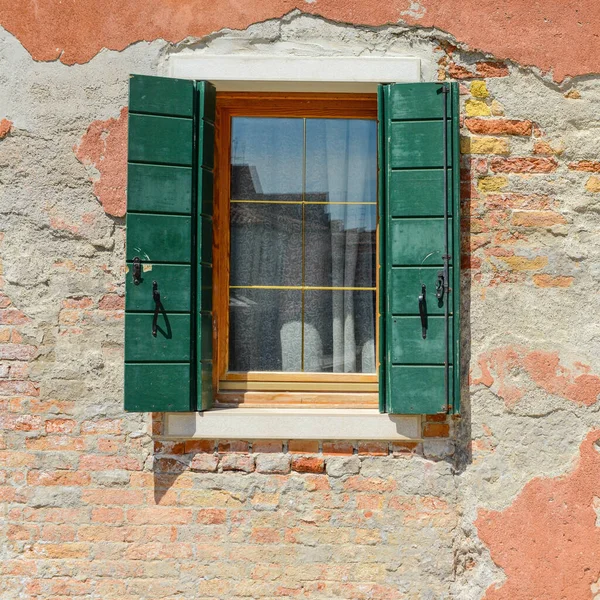意大利布尔诺市橙色旧房屋墙壁上的绿色窗户混凝土中可见的红砖裂缝 — 图库照片