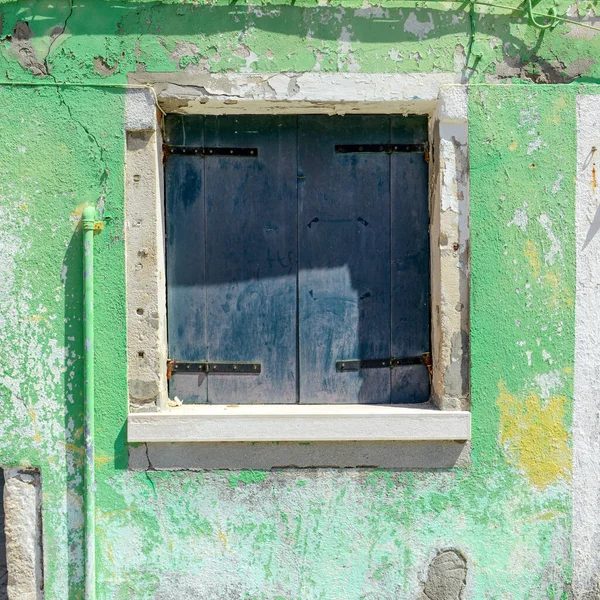Green window on green old house wall in Burano Island, Italy