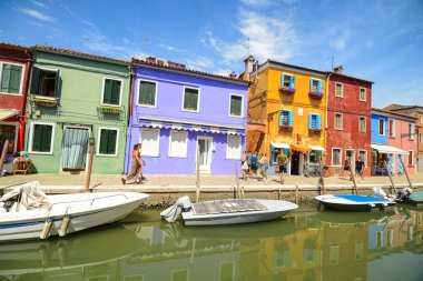 BURANO ISLAND, VENICE, ITALY - JULY 4, 2022: Tourists among the sovereign shops on the main street of burano Island,  Colorful houses on the canal. Famous travel destination. 