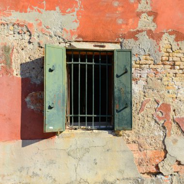 Green window on orange old house wall Cracks in concrete visible red bricks in Venice, Italy