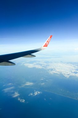 Phuket, Thailand - November 8, 2022: A wing of plane in the sky. Beautiful view of blue sky above the white clouds from airplane window of Air Asia.	