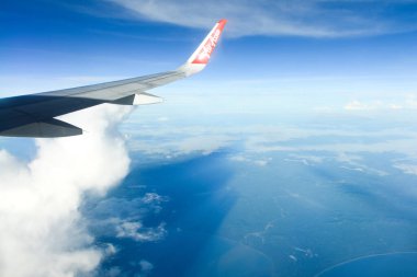 Phuket, Tayland - 8 Kasım 2022: Gökyüzünde bir uçak kanadı. Air Asia 'nın uçak penceresinden beyaz bulutların üzerindeki güzel mavi gökyüzü manzarası