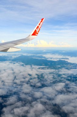Phuket, Thailand - November 8, 2022: A wing of plane in the sky. Beautiful view of blue sky above the white clouds and land from airplane window of Air Asia.	