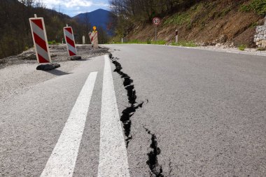 Erozyon ya da depremin yol açtığı uzun çatlaklarla dolu asfalt yol. Hasarlı asfalt yol, dağdaki tek şeritte sınırlı hareket.