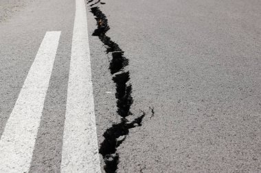Erozyon ya da depremin yol açtığı uzun çatlaklarla dolu asfalt yol. Hasarlı asfalt yol, dağdaki tek şeritte sınırlı hareket.