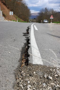 Erozyon ya da depremin yol açtığı uzun çatlaklarla dolu asfalt yol. Hasarlı asfalt yol, dağdaki tek şeritte sınırlı hareket.