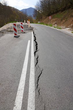 Erozyon ya da depremin yol açtığı uzun çatlaklarla dolu asfalt yol. Hasarlı asfalt yol, dağdaki tek şeritte sınırlı hareket.