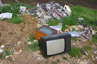 Hurdalıkta eski bir televizyon seti. Çöpe atılmış bozuk TV, çevre kirliliği