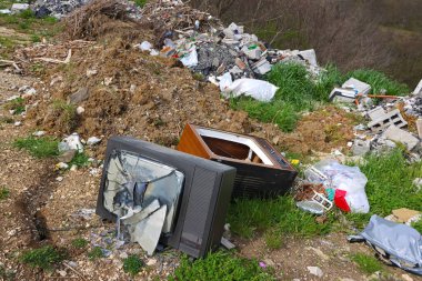 Hurdalıkta kırılmış eski bir televizyon seti. Kırık TV ekranı çöp yığını ve çevre kirliliği ile parçalandı