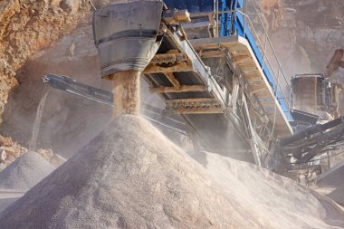 Çukur kazma ve ezilmiş taş işleme tesisinde taş kırma makinesi. Taşıyıcı bantlar ve çakıl taşı yığınları. Sanayi ve inşaat malzemeleri, kum ve çakıl kavramları
