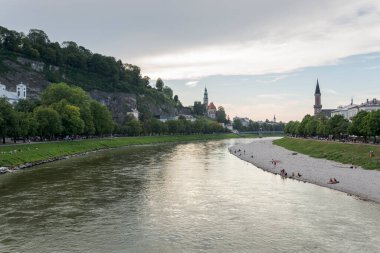SALZBURG, AUSTRIA - 28 Temmuz 2022: Marko-Feingold-Steg köprüsünden Salzach nehrinin manzarası. Mllner Kilisesi, Mllner Steg Köprüsü ve Christuskirche Protestan Kilisesi görülebilir.