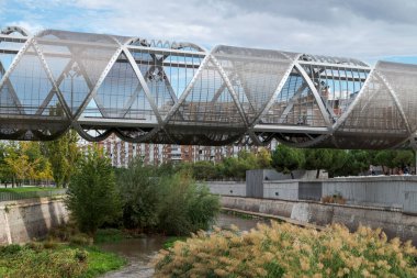 MADRID, İspanya - 22 Ekim 2022 Arganzuela Köprüsü. Dominique Perrault tarafından tasarlanmış, 274 metre uzunluğunda ve Manzanares nehri kıyısındaki Arganzuela Parkı 'na giriş izni veren bir tepe ile birbirine bağlı iki spiral şekilli geçitten oluşmuştur..