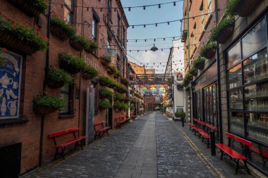 BELFAST, NORTHERN IRELAND - 4 AĞUSTOS 2024: Belfast 'ta yeşil tuğlalı binalar ve asılmış fabrikalar, banklar ve tepe ışıkları ile süslenmiş büyüleyici bir ticari cadde