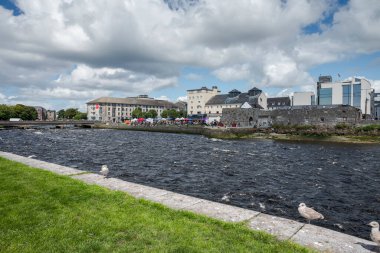 GALway, IRELAND - 6 AĞUSTOS 2023: Galway 'de renkli çadırları ve tezgahları olan canlı bir pazar sahnesi, insanlar sosyalleşiyor ve arka planda parçalı bulutlu gökyüzünün altındaki binalar