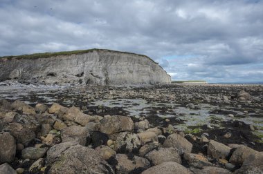 Silverstrand, Galway, İrlanda 'daki Rocky plajı. Büyük bir uçurum, parçalı bulutlu gökyüzü, ve sakin deniz, doğal güzellikler ve jeolojik özellikler sergiliyor.