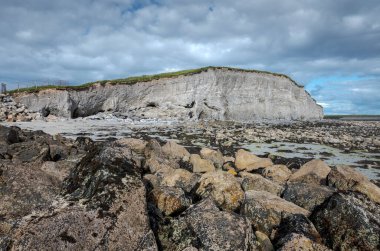 Silverstrand, Galway, İrlanda 'daki Rocky plajı. Büyük bir uçurum, parçalı bulutlu gökyüzü, ve sakin deniz, doğal güzellikler ve jeolojik özellikler sergiliyor.