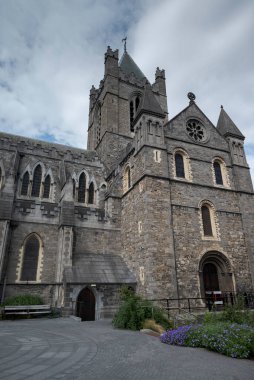 Dublin, İrlanda 'daki İsa Kilisesi Katedrali, Gotik mimarisi, kemerli pencereleri ve taş cepheleriyle parçalı bulutlu bir gökyüzüne karşı kurulmuş.