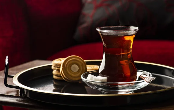 Turkish Tea presentation with biscuit on tray. Tea time for Turkish people. Turkish Tea in traditional glass on sunset time.