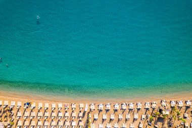 Deniz manzarası. Yazın güneşli bir günde güneşli yatakları ve şemsiyeleri olan boş kumlu bir sahil. Temiz turkuaz suyu ve güverte sandalyesi olan tropik bir manzara. Kemer, Antalya, Türkiye.