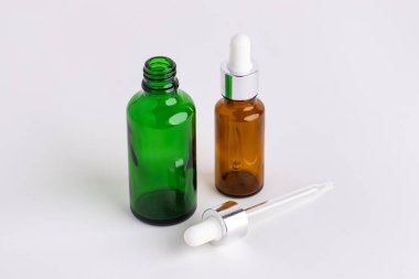 Beyaz arka planda izole edilmiş damlacıklı ya da pipetli renkli cam kozmetik yağ şişesi. Damla Duraklı Yuvarlak Şişe. 