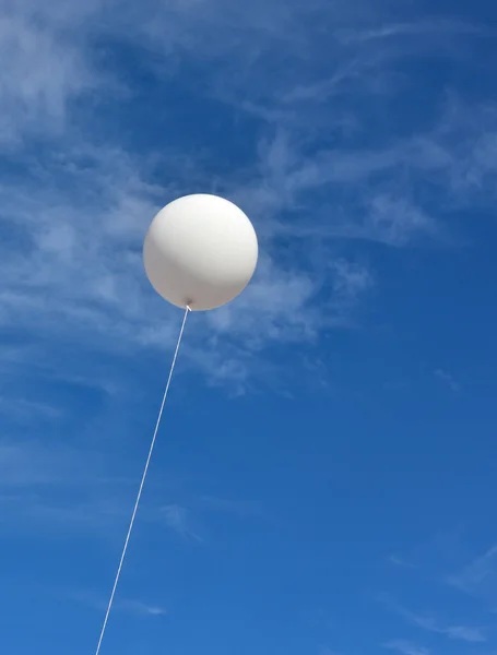 White balloon. A giant inflatable white advertising balloon floats in the sunny blue sky