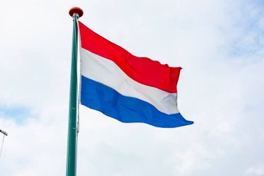 Hollanda bayrağı mavi gökyüzünde dalgalanıyor. Amsterdam, Hollanda. Hollanda Bayrağı.