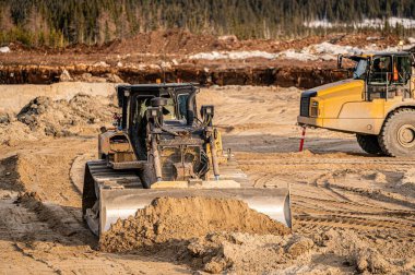 Boreal Ormanı 'ndaki bir kazının dibine kum iten buldozer.