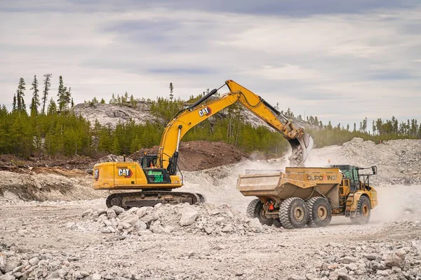 加拿大魁北克北部的Eleonore矿 2023 一辆挖掘机在加拿大北部的一个矿区装载一辆装有石块的倾卸卡车 免版税图库图片