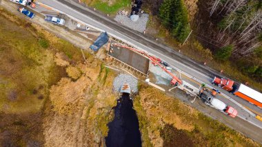 Beton pompa ile beton döşeme, bir taşra yolunda kırık bir kanal üzerinde acil durum levhası