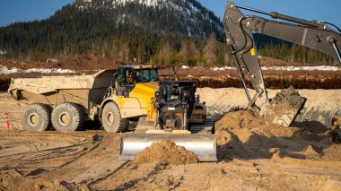 Buldozer, kazıcı yükleme noktasına çöp yolu için kum yerleştiriyor.