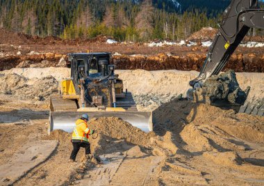 Bir ustabaşı buldozer ve kazıcının çalışma alanından geçer.