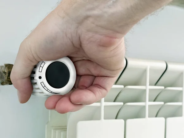 サーモスタットを使用して部屋の中央加熱ラジエーター温度を下げる男性の手の閉鎖 — ストック写真