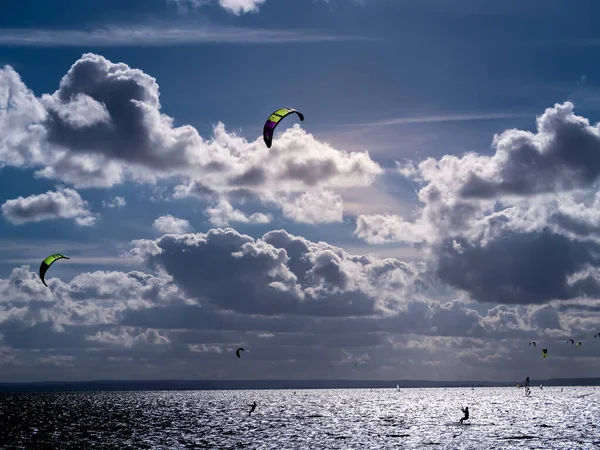 Backlit silhouettes of many kitesurfers surfing on the sea, Jastarnia, Poland
