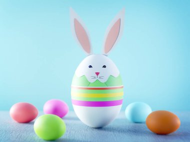 Yumurtadan yapılmış 3 boyutlu Paskalya tavşanı. Mavi arkaplanda kağıt kesme süsleri var.