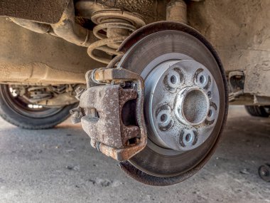 Arka tekeri sökülmüş asansördeki yolcu aracı fren diskini çıkarıyor.