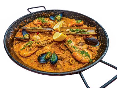 Geleneksel İspanyol deniz ürünleri yemeği Paella, siyah bir tavada, midye ve karides ile birlikte, beyaz üzerine izole edilmiş.