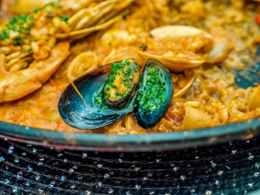 Geleneksel İspanyol deniz ürünleri yemeği Paella siyah bir tavada midye ve karidesli pilav.